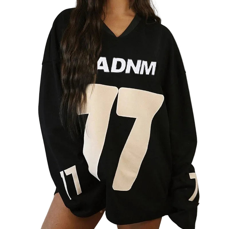 Close-up view of a model wearing the loose-fit black "BADNM 77" streetwear jersey pullover, showcasing its relaxed drape and deep V-neckline.