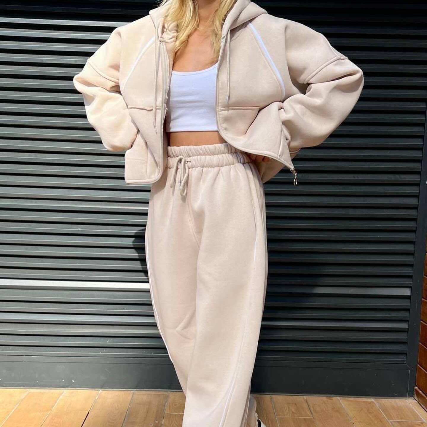 Alternate front angle of the model wearing the neutral beige two-piece athleisure tracksuit with a white crop top underneath.