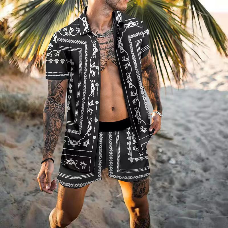 Man modeling the MONTQUANT two-piece resort set on a beach background, featuring an intricate dark grey and black baroque graphic layout.