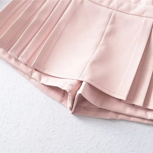 Close-up fabric shot focusing on the clean hemline and structured knife pleats of the pink skort.