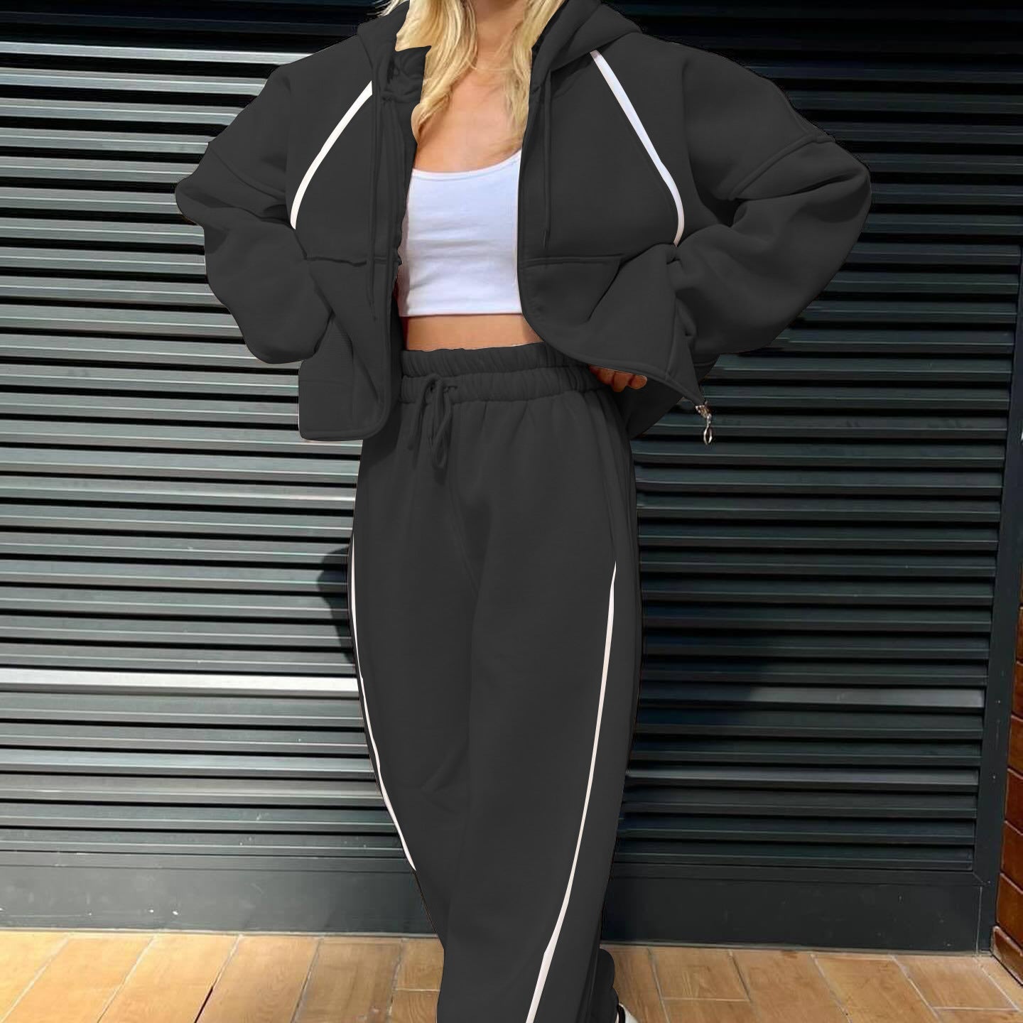 Front view of the minimalist two-piece tracksuit set in matte black, accented by a stark white contrast stripe along the outer seams.