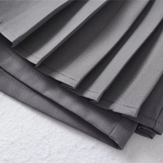 Close-up macro shot of the dark grey fabric and precise pleating details.