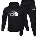 Front view of the MONTQUANT Fleece Pullover Tracksuit Set in monochrome black, showcasing the matching hoodie and joggers with contrast white graphic logos on the chest and thigh.
