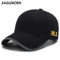 Front profile shot of MontQuant's signature structured cotton baseball cap in matte black, showcasing the curved brim with white geometric contrast stitching and subtle gold side embroidery.