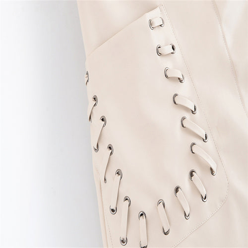 Detailed close-up view of the metal grommets and criss-cross string tie detailing on the beige skirt