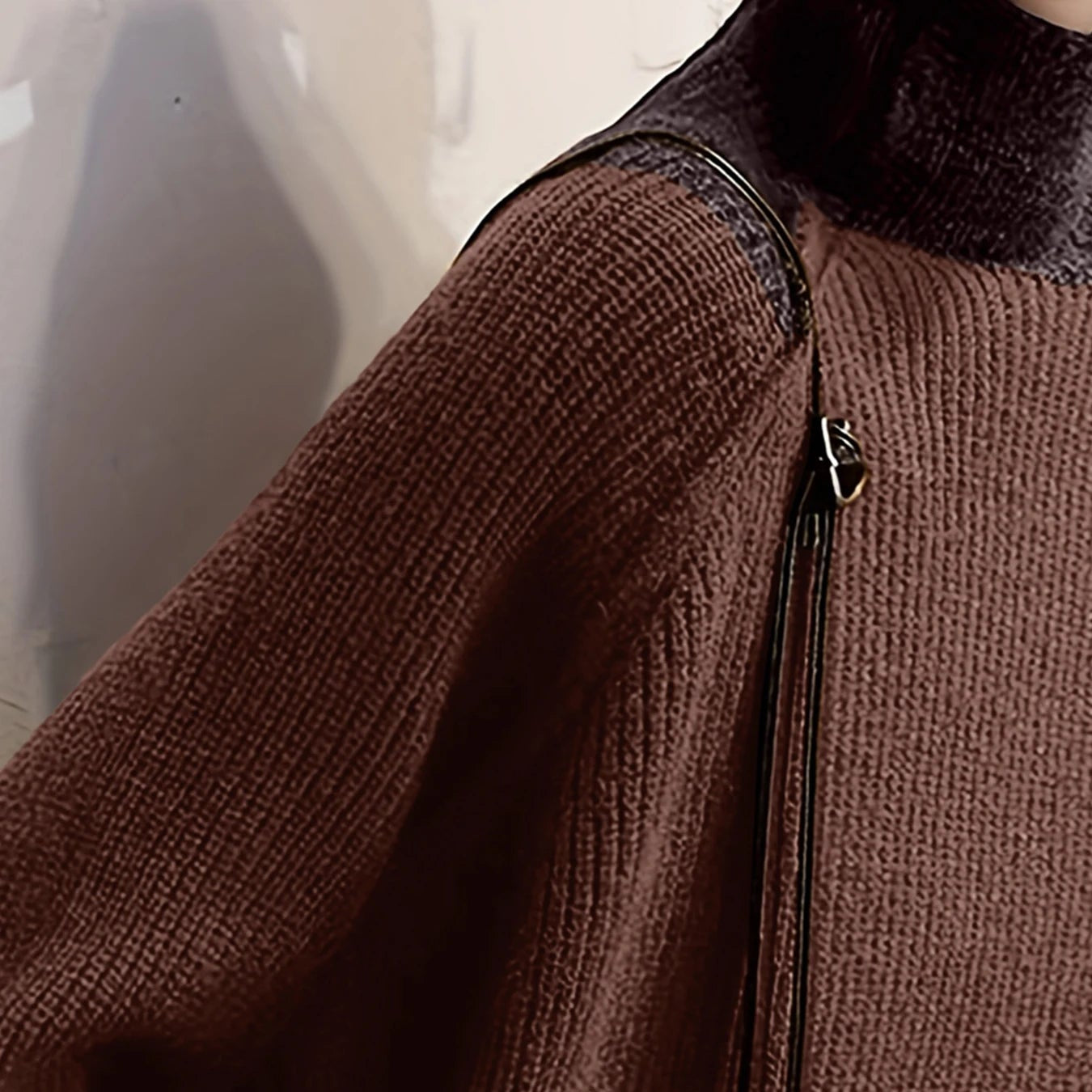 Close-up detail of the textured knit pattern and structural shoulder seam on the brown patchwork sweater.
