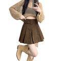 On-model shot featuring the brown skirt paired with a grey knit sweater and tall tan boots.