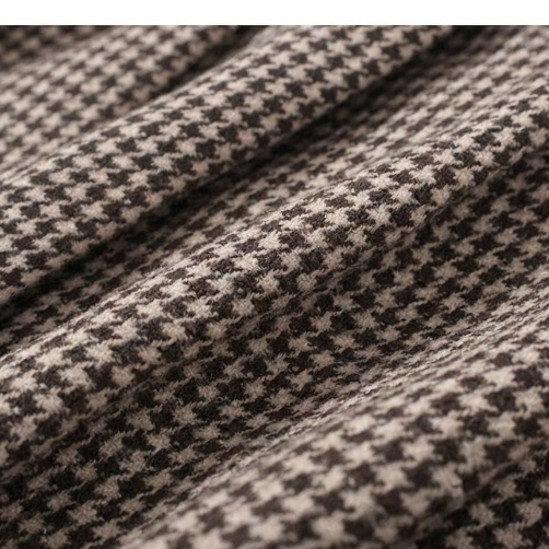 Close-up detail of the classic houndstooth patterned fabric, pleating structure, and belt loops